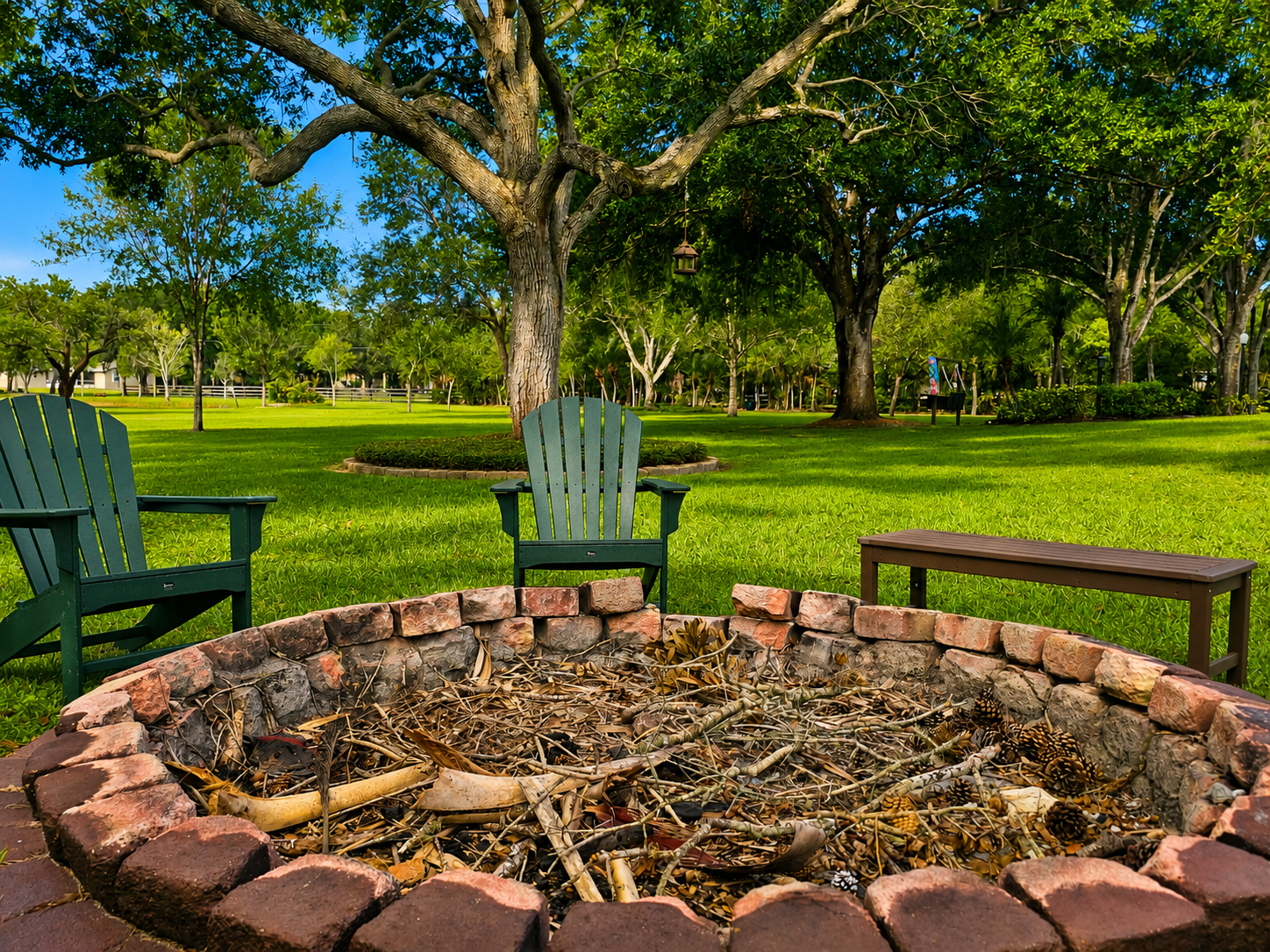 Stone fire pit with Adirondack chairs under mature oaks