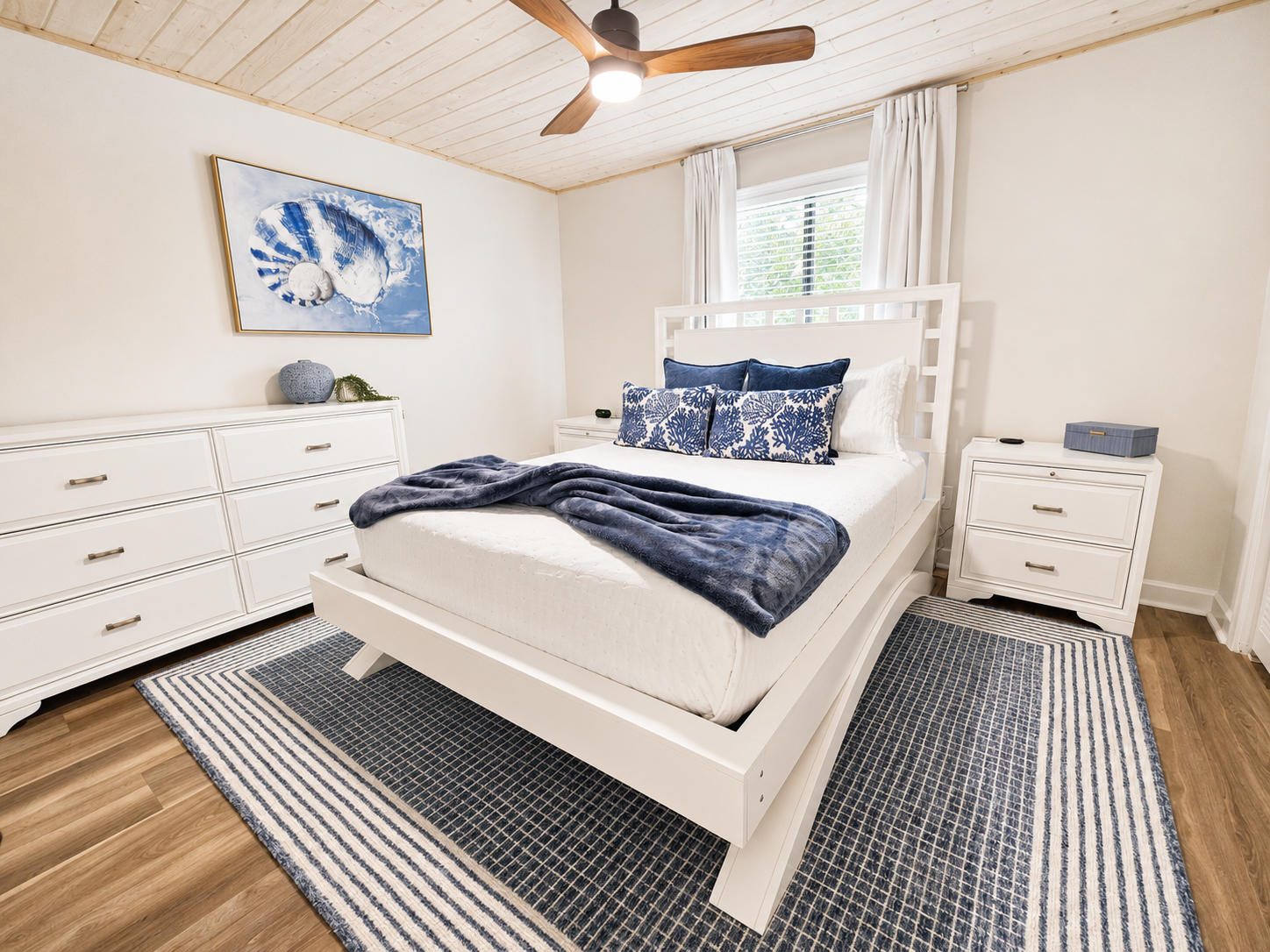 Bright bedroom with white furnishings, blue accents and ceiling fan